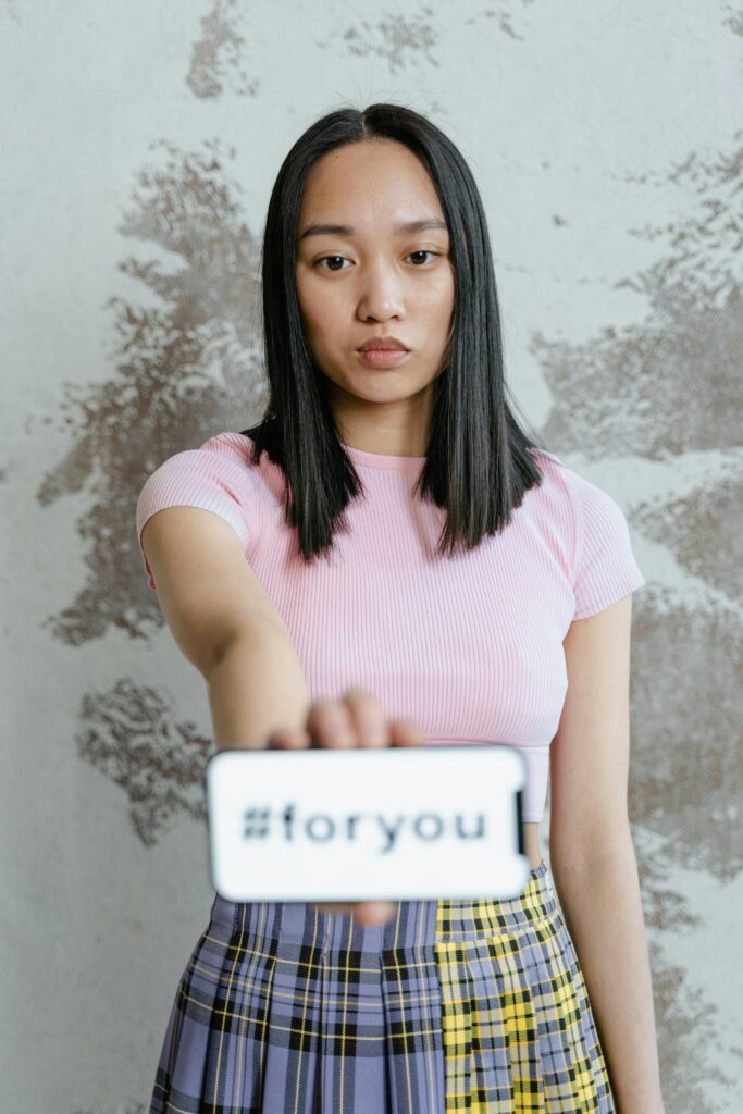 Young woman showing hashtag message on smartphone indoors, trendy and casual.